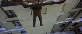 Movie still from “The Bourne Identity” (2002), directed by Doug Liman – A man hanging from the side of a building holding onto a beam; Wide shot, Overhead angle