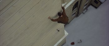 Movie still from “The Bourne Identity” (2002), directed by Doug Liman – A man in a brown jacket is jumping off a ledge; Wide shot, Overhead angle