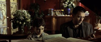 Movie still from “The Bourne Identity” (2002), directed by Doug Liman – A young boy sitting in front of a sheet of music; Medium shot, Over the shoulder angle