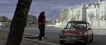 Movie still from “The Bourne Identity” (2002), directed by Doug Liman – A woman standing next to an old car on the side of the road; Wide shot, Over the shoulder angle