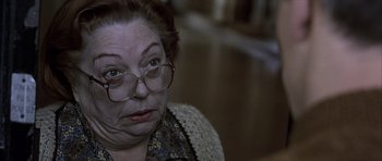 Movie still from “The Bourne Identity” (2002), directed by Doug Liman – An older woman wearing glasses looking at the camera; Close Up shot, High angle