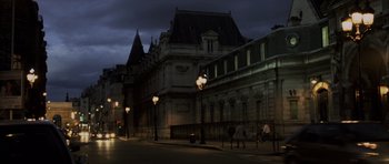 Movie still from “The Bourne Identity” (2002), directed by Doug Liman – People walking down the street at night in front of a large building; Extreme Wide shot, Low angle