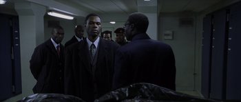 Movie still from “The Bourne Identity” (2002), directed by Doug Liman – A man in a suit and tie standing next to another man in a suit and tie; Medium shot, Over the shoulder angle