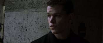 Movie still from “The Bourne Identity” (2002), directed by Doug Liman – A young man is standing in front of a concrete wall; Close Up shot, Low angle