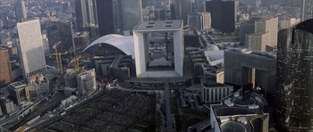Movie still from “The Bourne Identity” (2002), directed by Doug Liman – An aerial view of a large building in the middle of a city; Extreme Wide shot, High angle