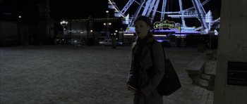 Movie still from “The Bourne Identity” (2002), directed by Doug Liman – A woman standing in front of a ferris wheel at night; Wide shot, Over the shoulder angle