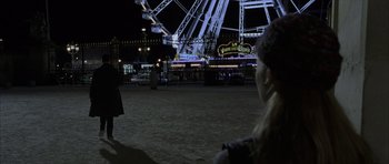 Movie still from “The Bourne Identity” (2002), directed by Doug Liman – Two people are standing in front of a ferris wheel at night; Wide shot, Over the shoulder angle