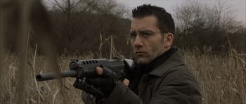 Movie still from “The Bourne Identity” (2002), directed by Doug Liman – A man holding a gun while standing in a field; Close Up shot, Low angle