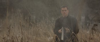 Movie still from “The Bourne Identity” (2002), directed by Doug Liman – A man in a black jacket holding something in his hand; Medium shot, Low angle