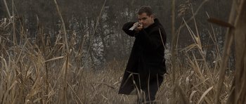 Movie still from “The Bourne Identity” (2002), directed by Doug Liman – A man in a black coat is standing in a field; Medium shot, Low angle