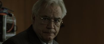 Movie still from “The Bourne Identity” (2002), directed by Doug Liman – An older man wearing glasses and a suit; Close Up shot, Low angle