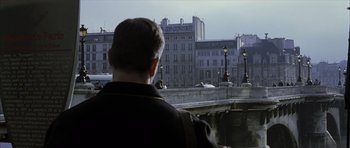 Movie still from “The Bourne Identity” (2002), directed by Doug Liman – A man standing on the side of a bridge looking at buildings; Medium shot, Over the shoulder angle