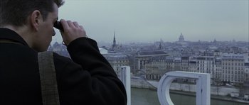 Movie still from “The Bourne Identity” (2002), directed by Doug Liman – A person standing on a bridge looking at a city skyline; Medium shot, Over the shoulder angle