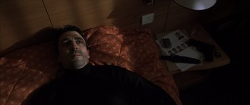 Movie still from “The Bourne Identity” (2002), directed by Doug Liman – A man laying on a bed looking up at the camera; Close Up shot, High angle