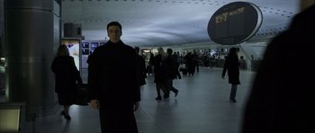 Movie still from “The Bourne Identity” (2002), directed by Doug Liman – A man wearing a black robe in an airport terminal; Medium shot, Low angle