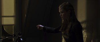 Movie still from “The Bourne Identity” (2002), directed by Doug Liman – A woman is holding a hand in a dark room; Medium shot, Low angle