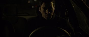 Movie still from “The Bourne Identity” (2002), directed by Doug Liman – A man sitting in the driver's seat of a car at night; Close Up shot, Low angle