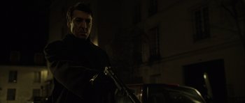 Movie still from “The Bourne Identity” (2002), directed by Doug Liman – A man with a gun standing next to a building; Close Up shot, Low angle