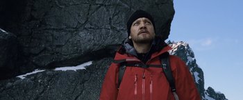 Movie still from “The Bourne Legacy” (2012), directed by Tony Gilroy – A man in a red jacket looking up at the sky; Medium shot, Low angle