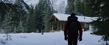 Movie still from “The Bourne Legacy” (2012), directed by Tony Gilroy – Two people walking in the snow near a log cabin; Wide shot, Low angle