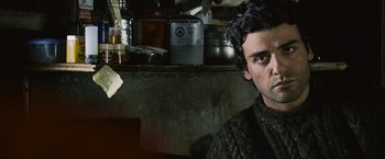 Movie still from “The Bourne Legacy” (2012), directed by Tony Gilroy – A man in a sweater sitting in front of pots and pans on a counter; Close Up shot, Over the shoulder angle