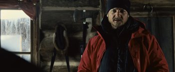 Movie still from “The Bourne Legacy” (2012), directed by Tony Gilroy – A man wearing a red jacket standing in front of a log cabin; Close Up shot, Low angle