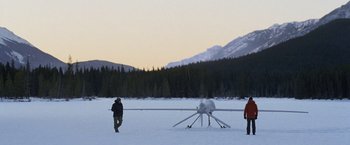 Movie still from “The Bourne Legacy” (2012), directed by Tony Gilroy – Two people standing in the snow near a small plane; Extreme Wide shot, High angle