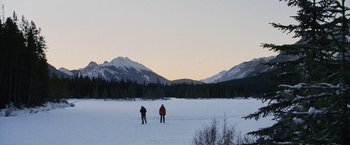 Two people standing in the middle of a snow covered field