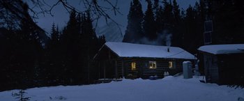Movie still from “The Bourne Legacy” (2012), directed by Tony Gilroy – A log cabin in the snow at night with lights on; Extreme Wide shot, High angle