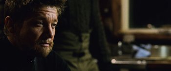 Movie still from “The Bourne Legacy” (2012), directed by Tony Gilroy – A person sitting in front of a wall; Close Up shot, Over the shoulder angle