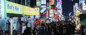 Movie still from “The Bourne Legacy” (2012), directed by Tony Gilroy – A crowd of people walking down a busy street at night; Extreme Wide shot, High angle