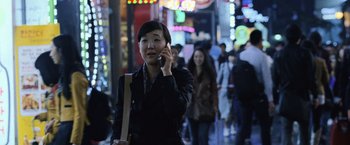 Movie still from “The Bourne Legacy” (2012), directed by Tony Gilroy – A woman talking on a cell phone while walking down the street; Medium shot, High angle