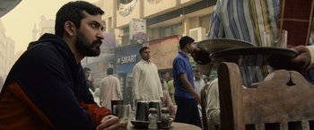 Movie still from “The Bourne Legacy” (2012), directed by Tony Gilroy – A group of people standing around a table with plates; Medium shot, Over the shoulder angle