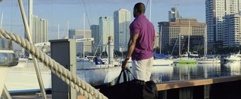 Movie still from “The Bourne Legacy” (2012), directed by Tony Gilroy – A man standing on a pier holding a bag of luggage; Wide shot, Low angle