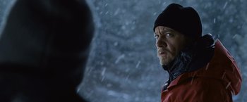 Movie still from “The Bourne Legacy” (2012), directed by Tony Gilroy – A person wearing a jacket and a hat; Close Up shot, Over the shoulder angle