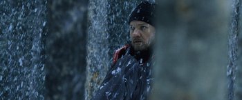 Movie still from “The Bourne Legacy” (2012), directed by Tony Gilroy – A man standing next to a tree in the snow; Close Up shot, Over the shoulder angle