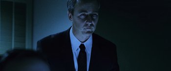 Movie still from “The Bourne Legacy” (2012), directed by Tony Gilroy – A man wearing a suit and tie in the dark; Close Up shot, Low angle