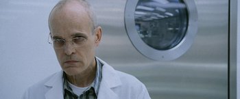 Movie still from “The Bourne Legacy” (2012), directed by Tony Gilroy – An older man wearing glasses and a white lab coat; Close Up shot, Low angle