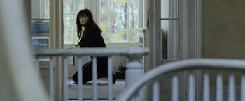 Movie still from “The Bourne Legacy” (2012), directed by Tony Gilroy – A woman sitting on the steps in front of a window; Wide shot, High angle