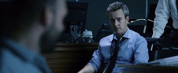 Movie still from “The Bourne Legacy” (2012), directed by Tony Gilroy – A man sitting in front of a computer desk; Medium shot, Over the shoulder angle