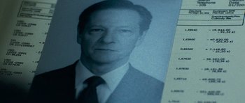 Movie still from “The Bourne Supremacy” (2004), directed by Paul Greengrass – An old photo of a man in a business suit; Extreme Close Up shot, Overhead angle