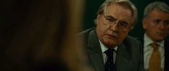 Movie still from “The Bourne Supremacy” (2004), directed by Paul Greengrass – An older man wearing a suit and tie; Close Up shot, Over the shoulder angle