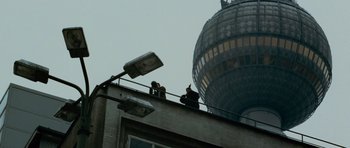 Movie still from “The Bourne Supremacy” (2004), directed by Paul Greengrass – Two people standing on the roof of an apartment building; Extreme Wide shot, Low angle