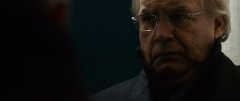 Movie still from “The Bourne Supremacy” (2004), directed by Paul Greengrass – An older man wearing glasses looking at the camera; Close Up shot, Over the shoulder angle