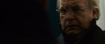 Movie still from “The Bourne Supremacy” (2004), directed by Paul Greengrass – An older man wearing glasses and a black jacket; Close Up shot, Over the shoulder angle