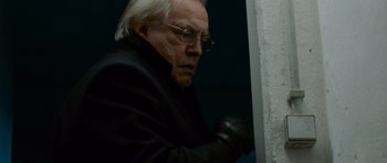 Movie still from “The Bourne Supremacy” (2004), directed by Paul Greengrass – An older man wearing glasses and a black jacket; Close Up shot, Low angle