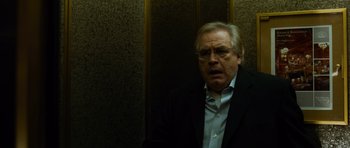 Movie still from “The Bourne Supremacy” (2004), directed by Paul Greengrass – An older man wearing a suit and glasses in an elevator; Close Up shot, Low angle