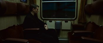 Movie still from “The Bourne Supremacy” (2004), directed by Paul Greengrass – A man sitting on a train looking out the window; Wide shot, Over the shoulder angle