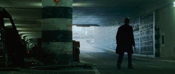 Movie still from “The Bourne Supremacy” (2004), directed by Paul Greengrass – A person walking in a tunnel with a light shining on it; Wide shot, Low angle