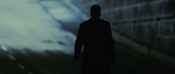 Movie still from “The Bourne Supremacy” (2004), directed by Paul Greengrass – A man in a black coat is holding a gun; Medium shot, Low angle